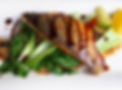 Pan fried fish on a bed of Pak Choi with a wedge of lime on a white plate
