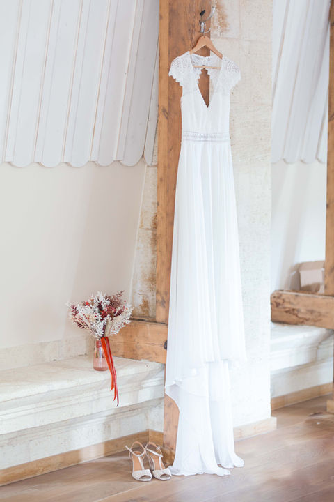 Robe de mariée blanche accrochée, bouquet et chaussures