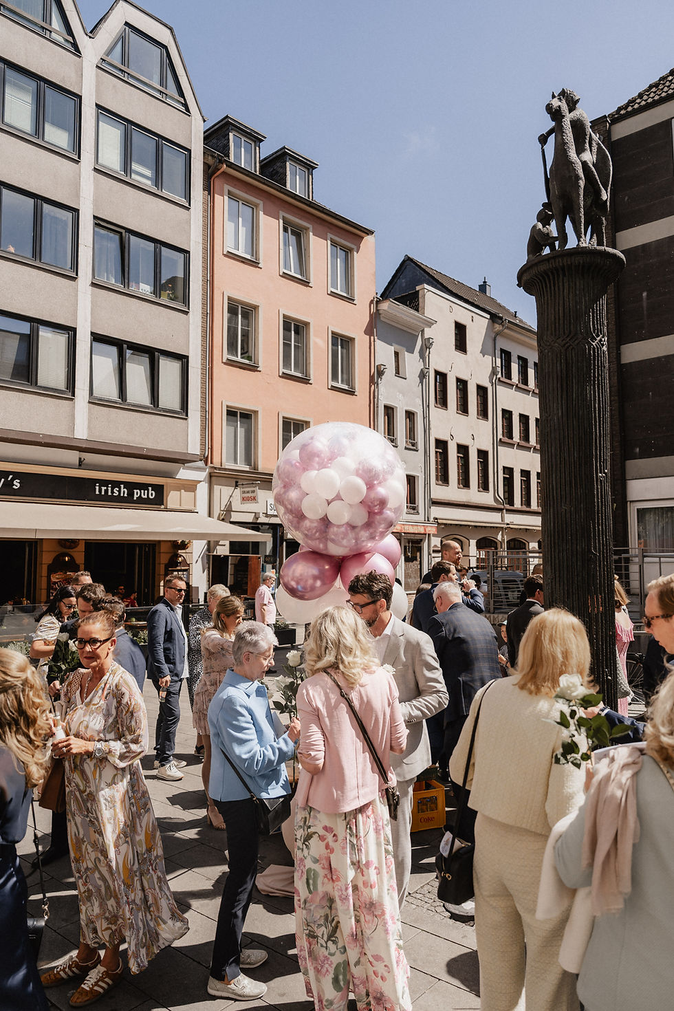 Hochzeitsgäste feiern in der Frankfurter Altstadt bei Sonnenschein, dekoriert mit rosafarbenen Ballons – lebendige Szene für Hochzeitsfilme in Frankfurt.