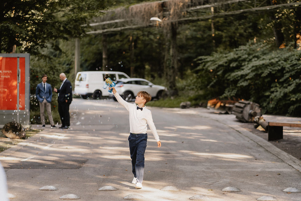 Junge im festlichen Outfit pustet Seifenblasen auf einer Straße während einer Hochzeit in Mainz – lebendiger Moment für Hochzeitsvideo Mainz.
