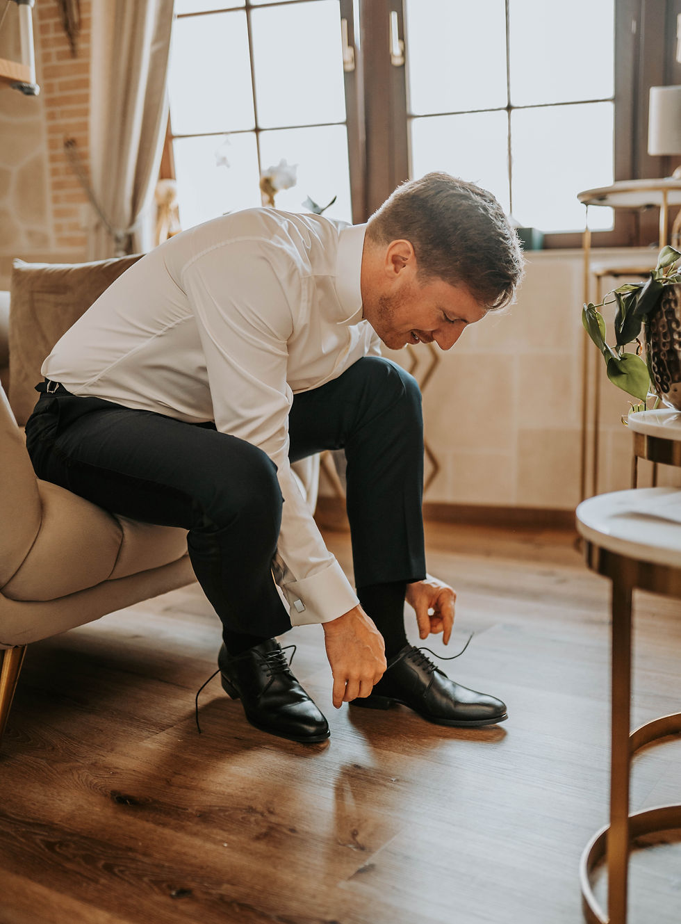 Bräutigam sitzt auf dem Sofa und bindet seine Schuhe während des Getting Ready – authentischer Moment für Hochzeitsvideo Mainz.