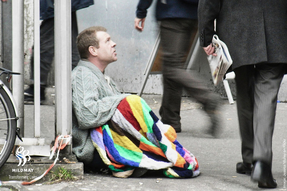 A photo by Jessica Mulley on Flickr of a seated homeless man watching passers-by