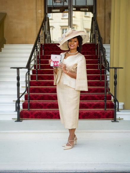 lady accepting OBE in cream hat