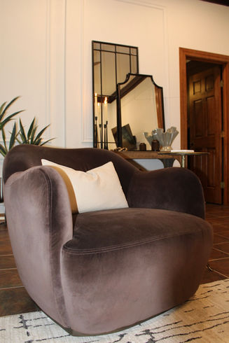Velvet accent chair in a refined lounge with layered mirrors, warm wood trim, and classic wall paneling.