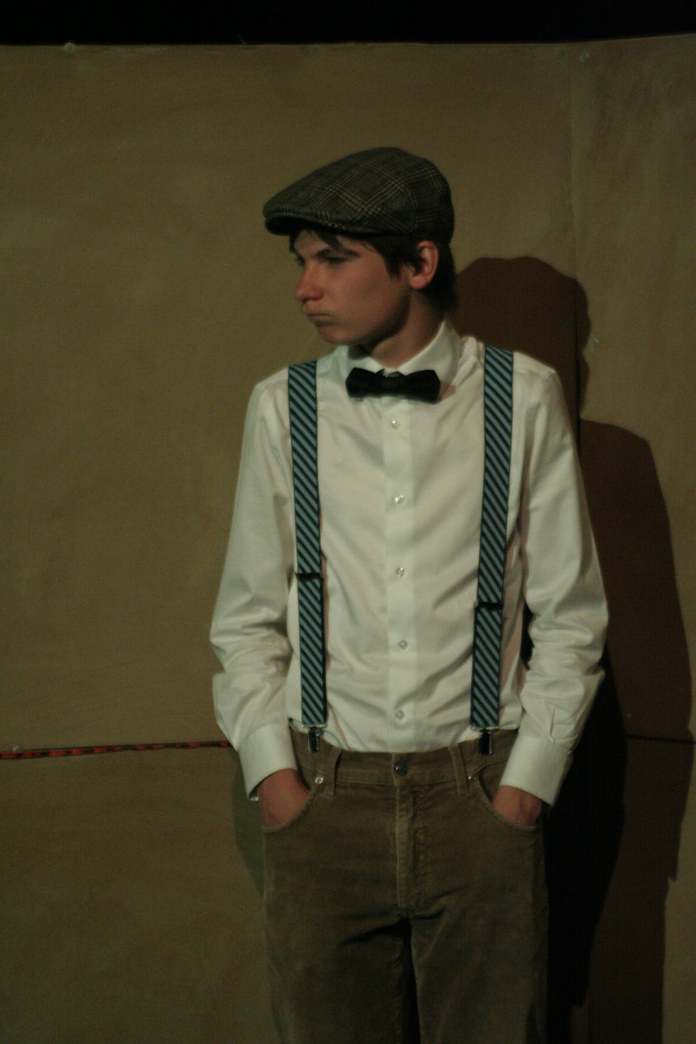 Ado en tenue des années 1920 sur une scène de théâtre.