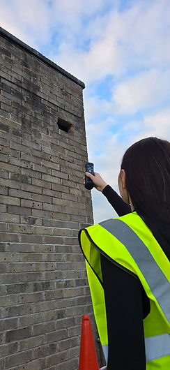 Technician inspects building wall damage with device