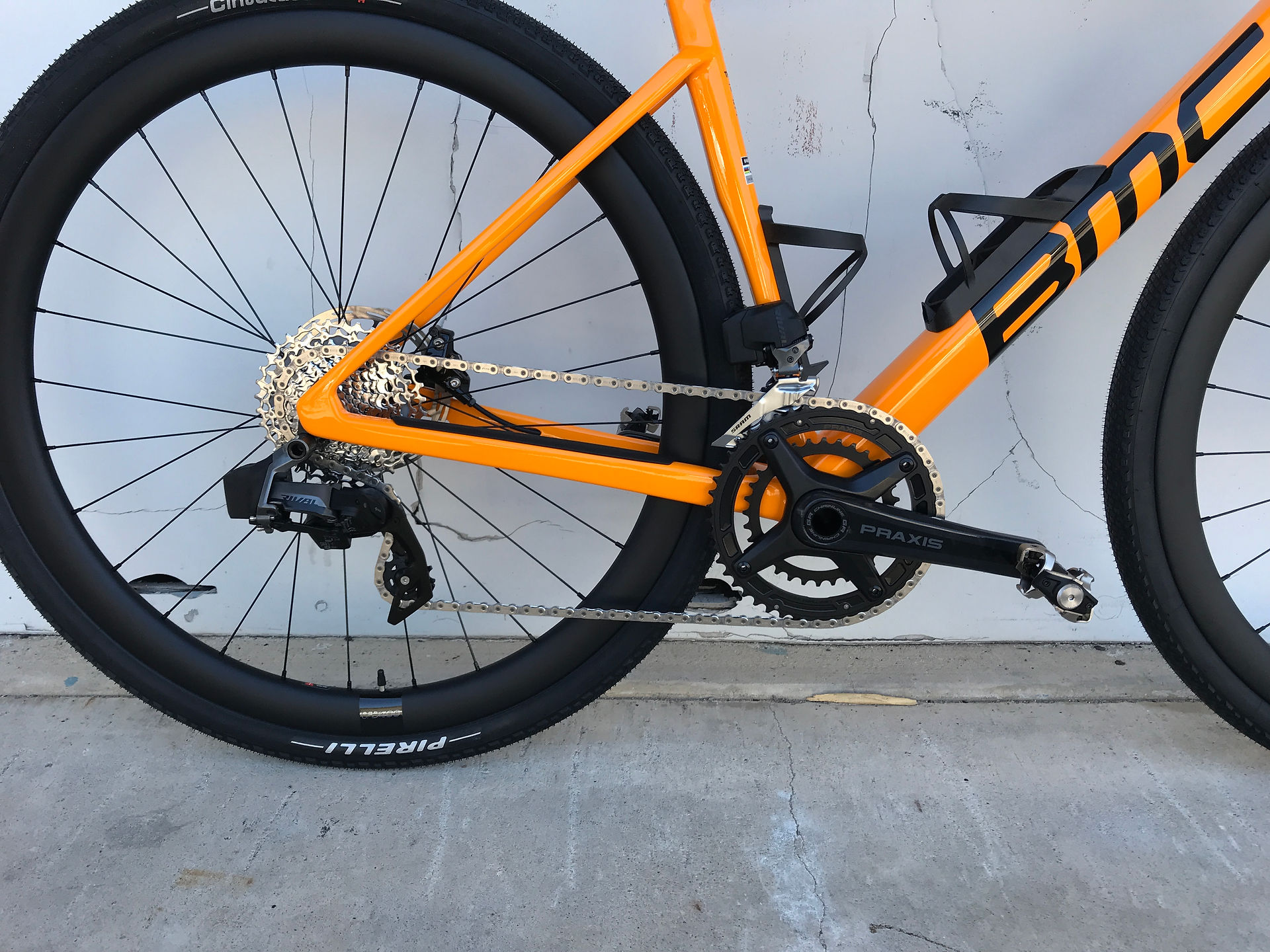 Orange BMC road bike Kaius model propped against white wall