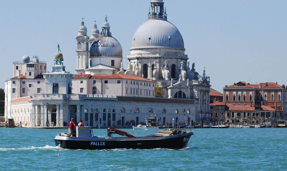 A small boat with Pall-Ex on the side travelling along the canal in Venice, with the Santa Maria Basilica in the background.