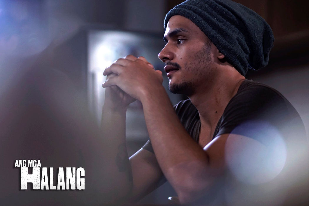 Man looking thoughtful with Ang Mga Halang title in the background. Ang Mga Halang The Movie.