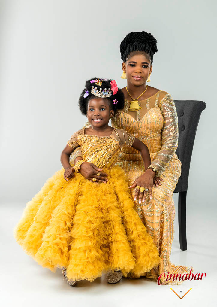 Mother and Daughter pose wearing beautiful golden yellow dresses during a studio portrait session.
