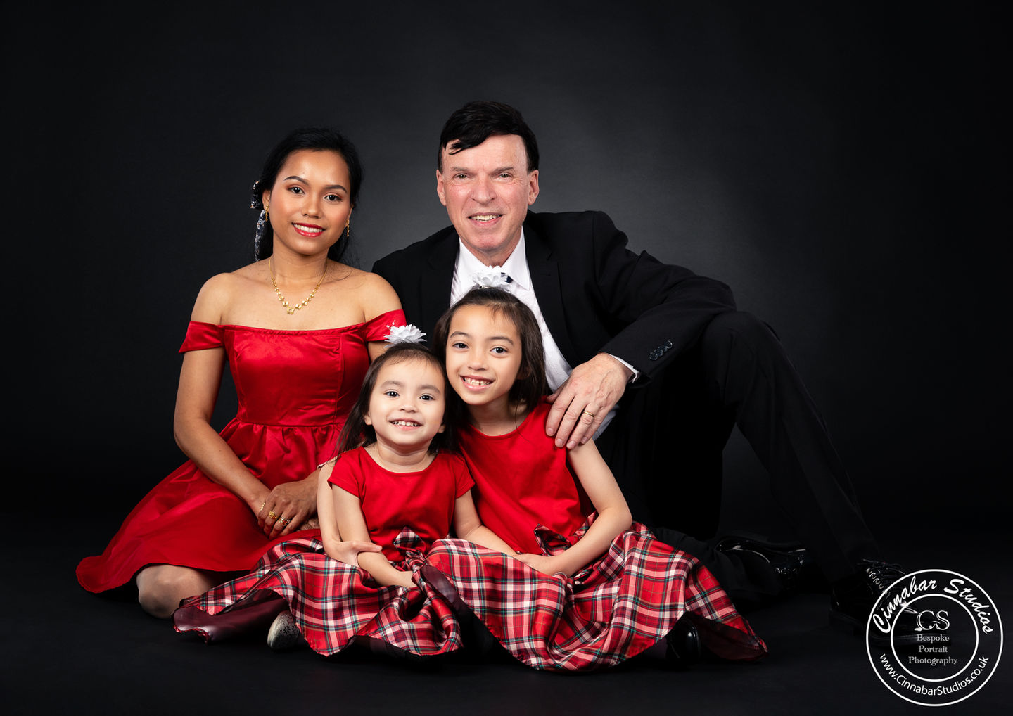 A studio portrait of a family wearing formal attire