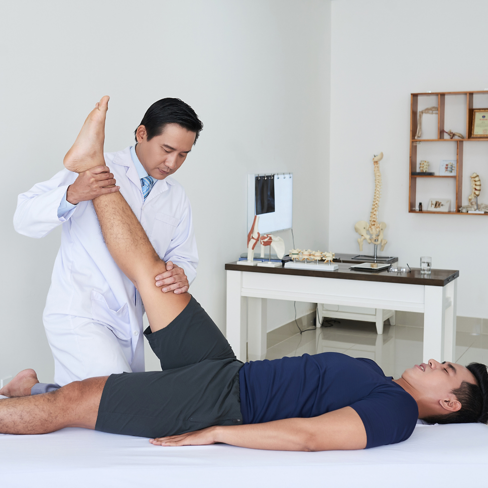 Doctor in a white coat stretches a man's raised leg in a clinic, with spine models and exam table in the background.