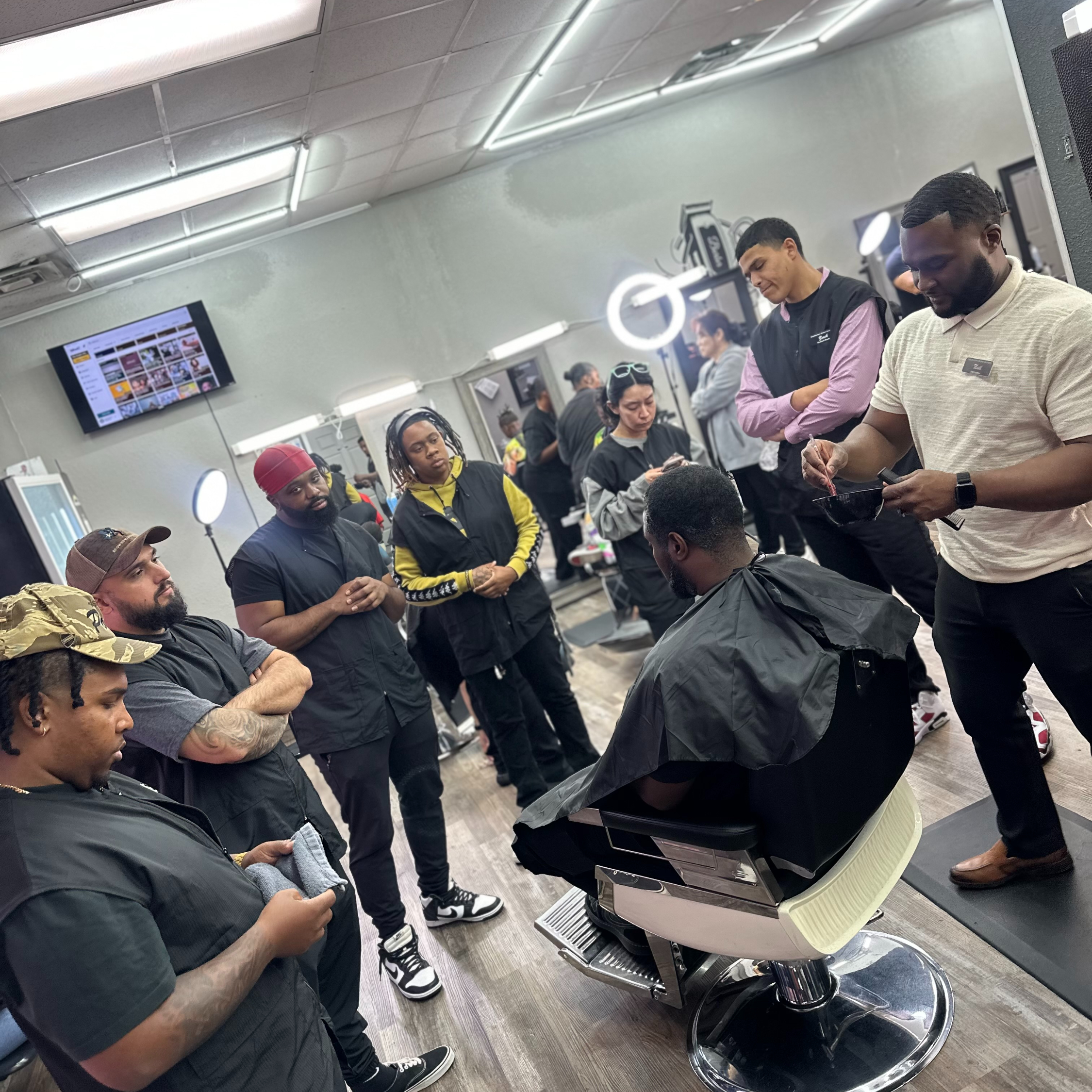 Barber instructor demonstrates a haircut while FadeMasterz students observe