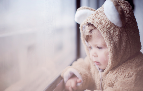 Kindje in berenpak kijkt door het raam