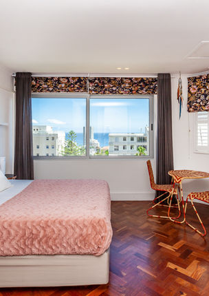 Bright hotel room with bed, desk, and window view.