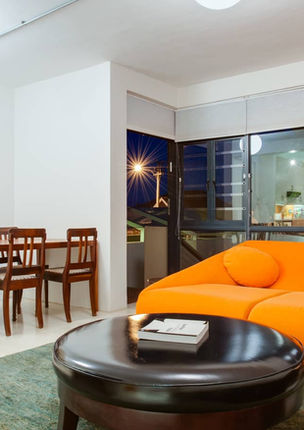 Living and dining space with orange sofa, round coffee table and large abstract painting