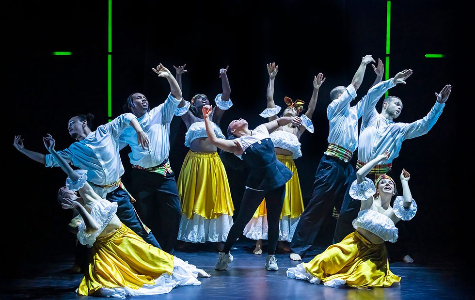 Dancers in white shirts and yellow skirts strike dynamic poses on stage, creating a vibrant and energetic atmosphere against a dark background.