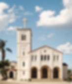 White Spanish Mission-style church with a bell tower and cross.