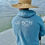 Thumbnail: Backside view of man on pier in Navarre Beach wearing the NAV BCH Lightweight Zip-up Hoodie in soundside blue color