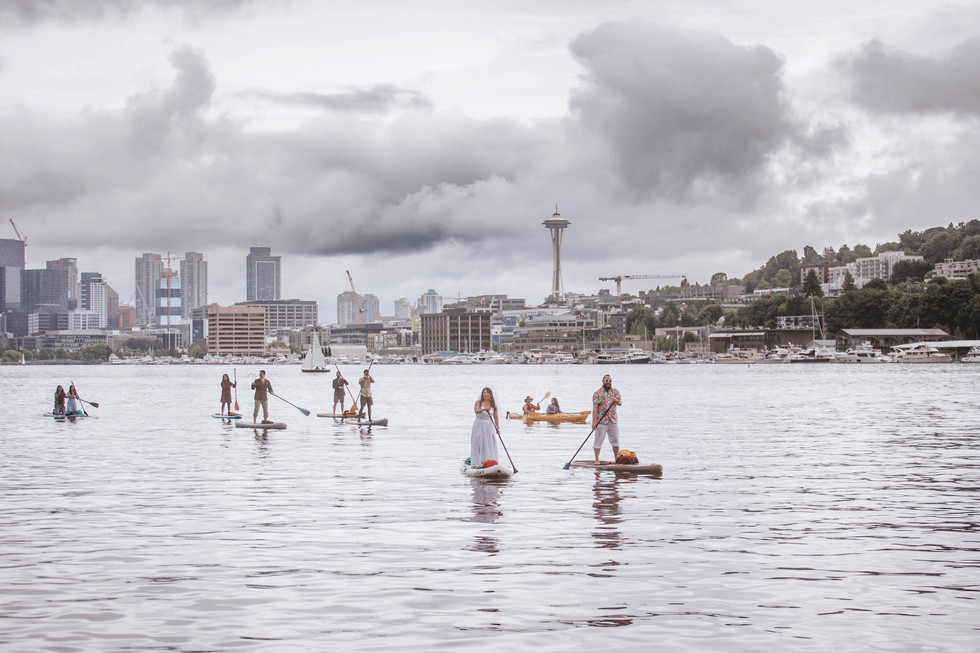 Epic bride and groom with wedding party paddleboarding into ceremony with Seattle in background Planner: Amethyst events