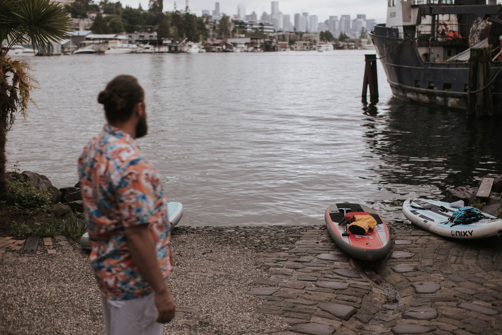 Groom in Hawaiian shirt gazing off into Waterway 15 and paddleboards