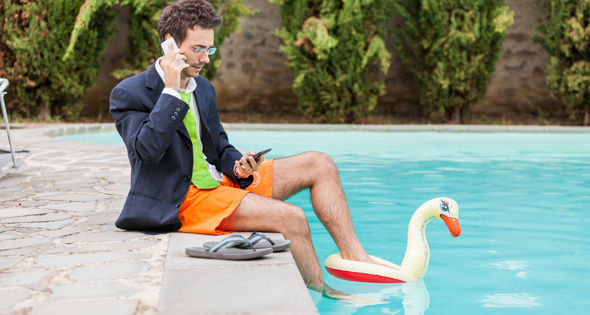 Persona revisando impuestos mientras viaja, con laptop, maleta y documentos de gastos.