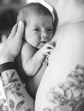 Neugeborenes liegt ruhig und sicher im Arm an Mamas Brust. Natürliche Neugeborenenfotos