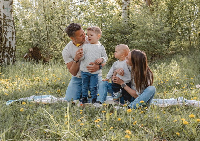 Familie mit zwei Kindern sitzt gemeinsam auf einer Decke im Grünen bei einem Familienshooting in Berlin