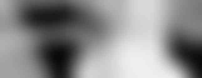 Menyasszonyi készülődés fekete fehérben. Menyasszony ül az ágyon, hosszú fátyla keretezi a képet.