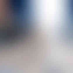 Világos szobában kockán szülinapi torta, rajta 1-es gyertya. Kék virágok, tégla fal, kék és fehér függöny