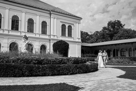 Kreatív esküvői fotózás Balatonfüreden az Anna Grand Hotel előtt - kézen fogva sétáló házaspár
