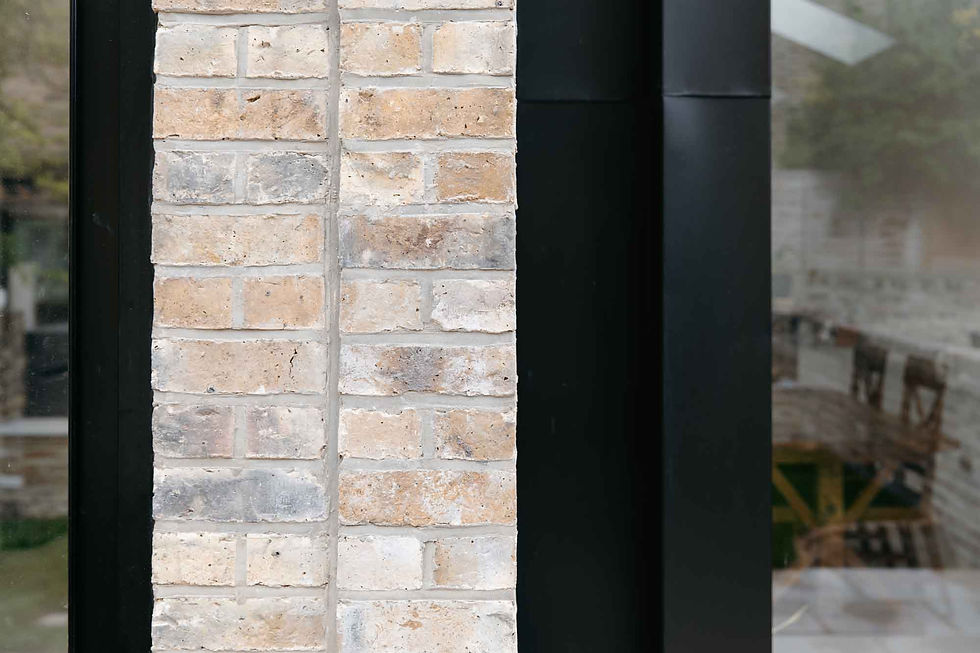 Connection detail showing black standing seam cladding meeting London brickwork.