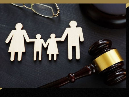 As pessoas de uma família recortadas em papel de mãos dadas com pai, mãe e dois filhos pequenos sobre uma mesa que também tem um martelo do poder judiciário