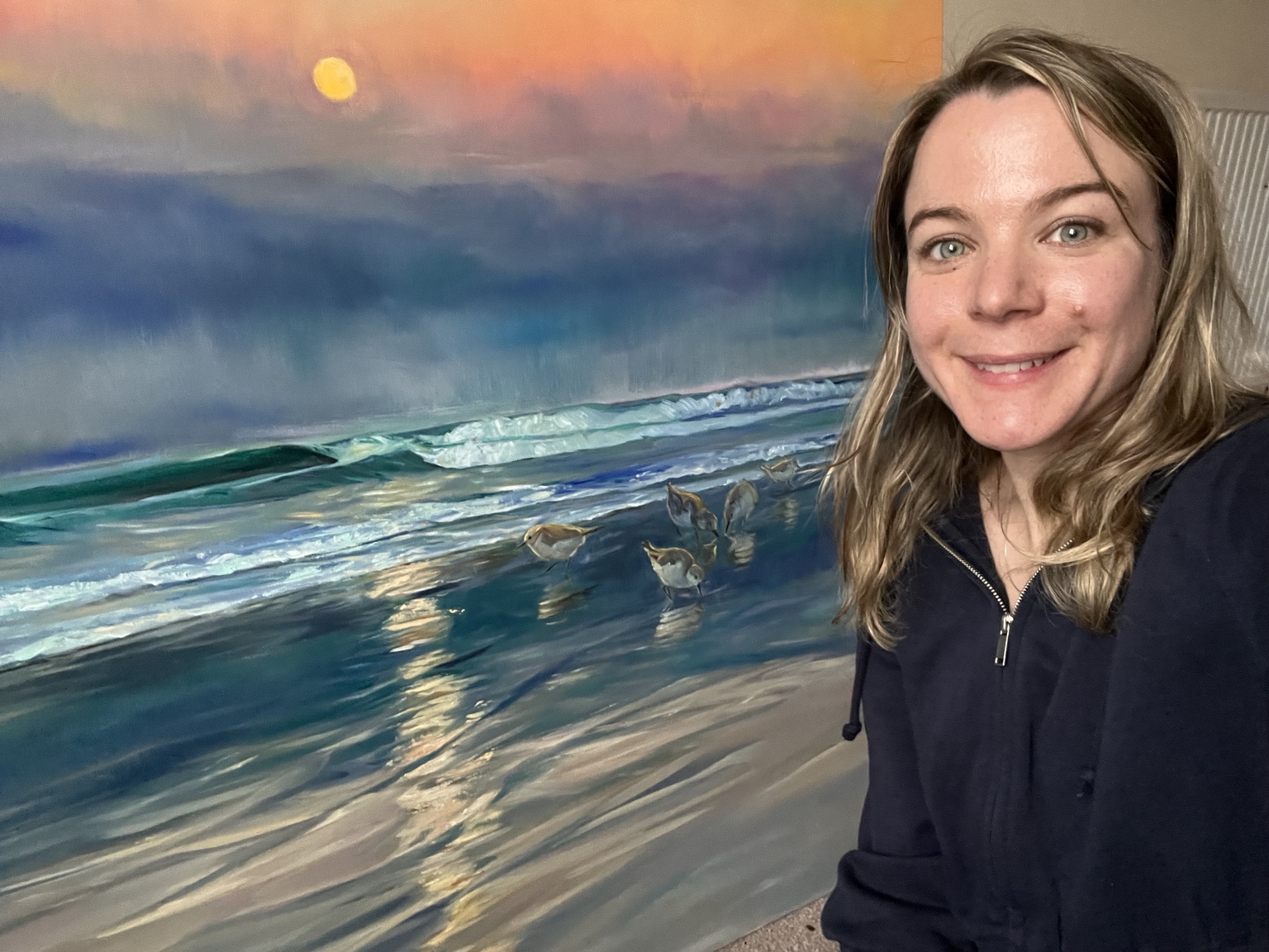 Jennifer Austin beside her painting Sanderlings at Sunset