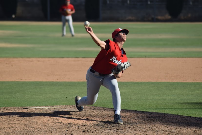 A right handed pitcher extends his arm beside his ear at full extension as he prepares to release a pitch.
