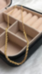 Corrente dourada torcida elegante dentro de uma caixa preta de joias.