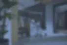Une femme accroupie réglant une machine à laver intégrée dans un grand dressing ou une buanderie moderne en bois sombre.