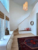 Modern entryway with wooden stairs and patterned rug.