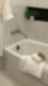 Modern bathtub with brass fixtures and white towels