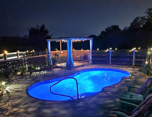 Lelani small fiberglass pool illuminated at night with backyard lighting