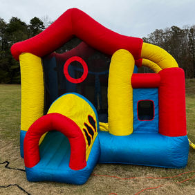 a photo of a red, yello, and blue bounce house with a tunnel entrance.