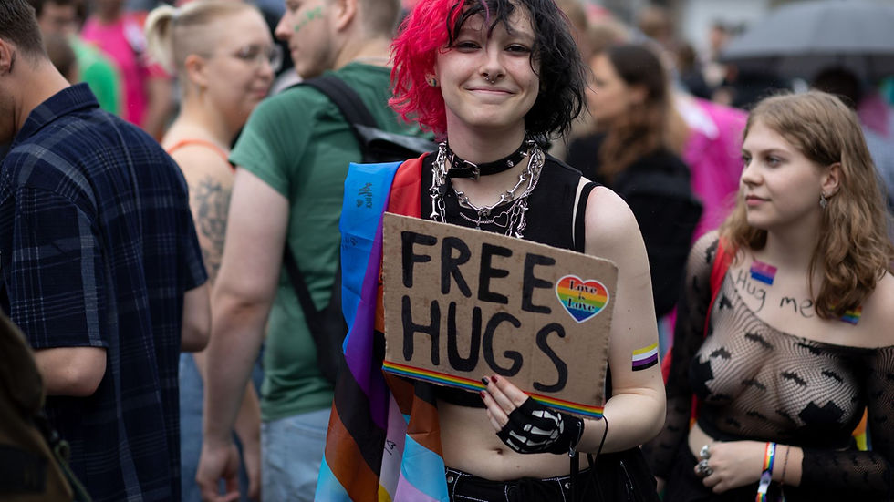 A smiling attendee at an LGBTQ+ festival offers free hugs, conveying love and acceptance.