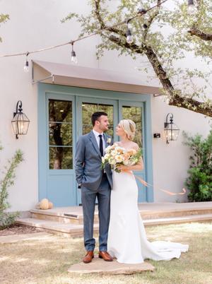 Bride and groom surrounded by florals of white orange and yellow roses at their wedding at The Wayback in austin texas