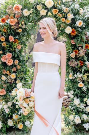 Bride and groom surrounded by florals of white orange and yellow roses at their wedding at The Wayback in austin texas