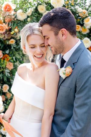 Bride and groom surrounded by florals of white orange and yellow roses at their wedding at The Wayback in austin texas