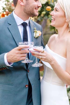 Bride and groom surrounded by florals of white orange and yellow roses at their wedding at The Wayback in austin texas
