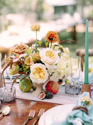 wedding reception table details of blue napkins and fall colored florals with blue taper candles