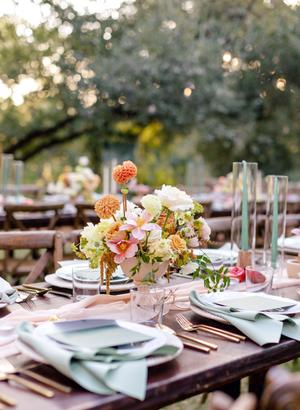 wedding reception table details of blue napkins and fall colored florals with blue taper candles