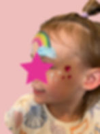 Girl with rainbow face paint and glitter tattoos
