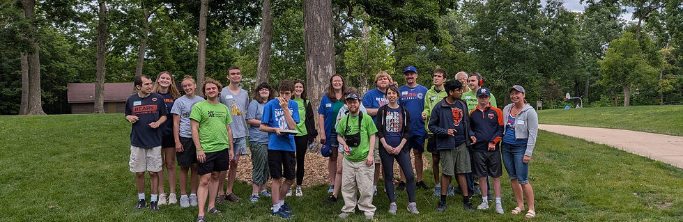 Large group of Community Access Naperville members and volunteers posing outdoors in a park, many wearing Chicago sports team shirts